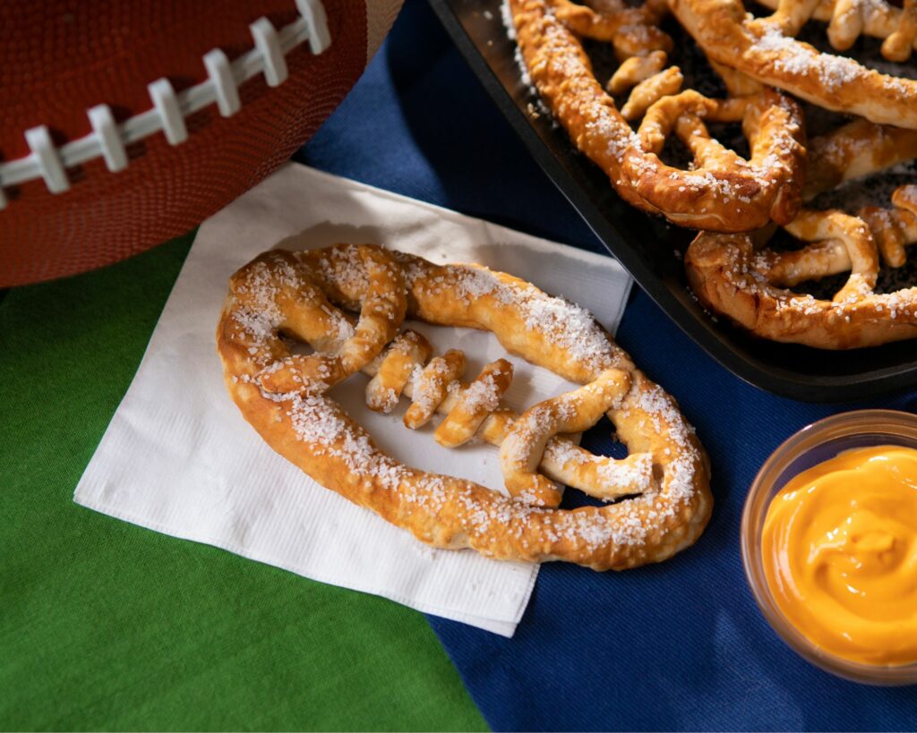 Football-shaped pretzels with cheese dip for a Superbowl celebration